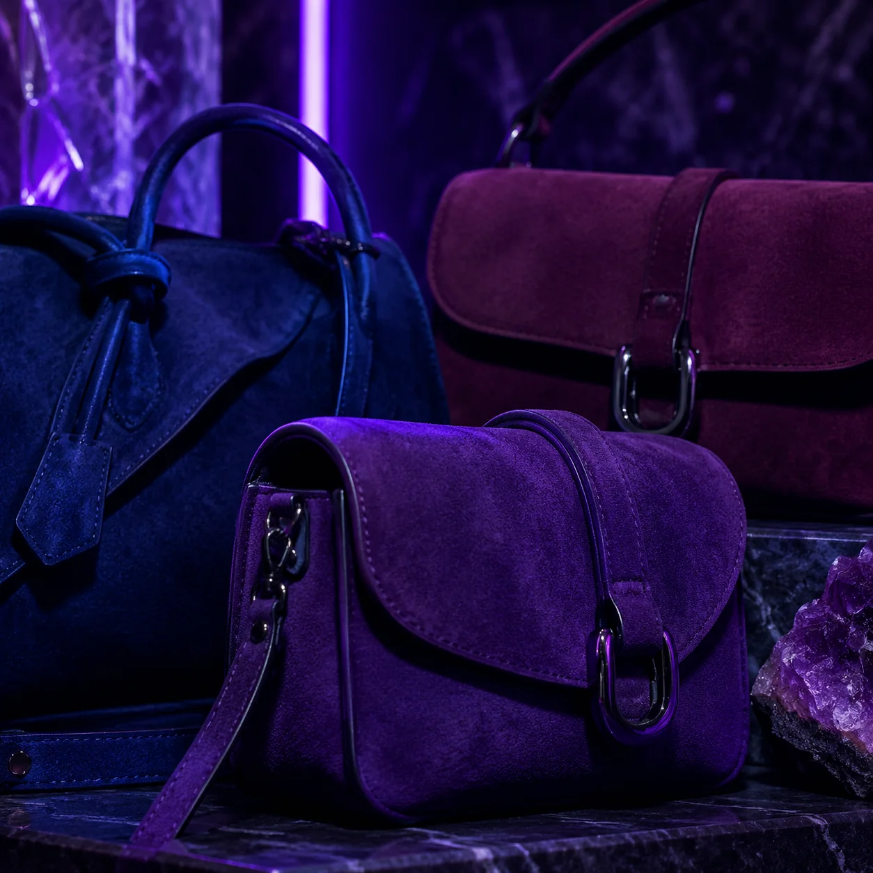 Varios bolsos de ante a medida en tonos joya sobre superficie oscura